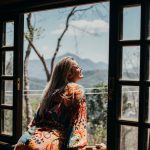 woman in red and white floral long sleeve shirt sitting on brown wooden chair