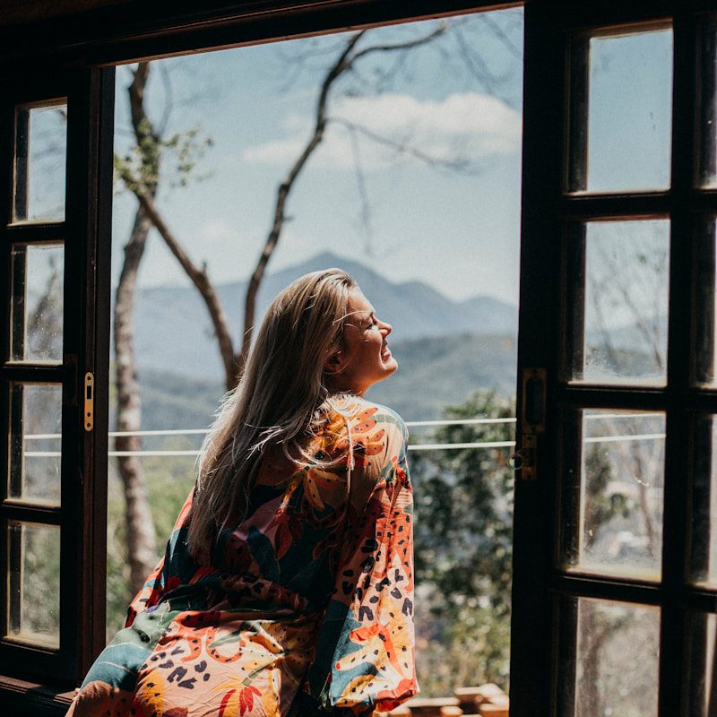 woman in red and white floral long sleeve shirt sitting on brown wooden chair